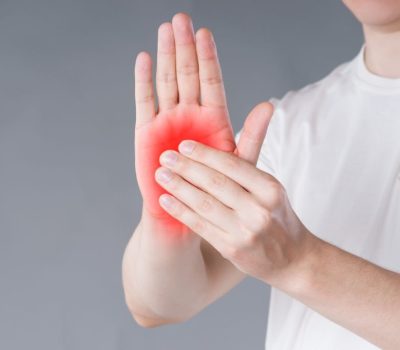 Pain in hand, carpal tunnel syndrome on gray background, painful area highlighted in red