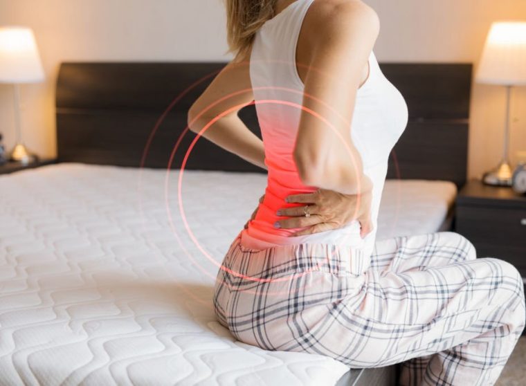 Caucasian ethnicity female suffering from back pain because of uncomfortable mattress