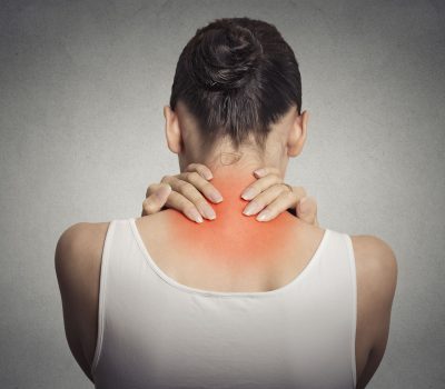 Healthy lifestyle. Back and spine disease. Closeup back view tired female massaging her neck colored in red isolated on gray background