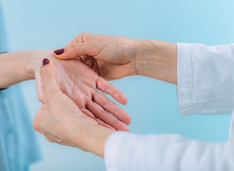 Doctor doing carpal tunnel syndrome test with a senior woman.
