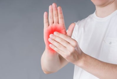 Pain in hand, carpal tunnel syndrome on gray background, painful area highlighted in red