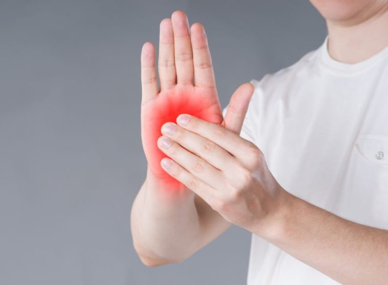 Pain in hand, carpal tunnel syndrome on gray background, painful area highlighted in red